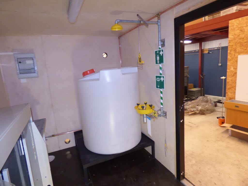 Vit tank och nöddusch i interiören på LCS vattenreningscontainer för processvatten