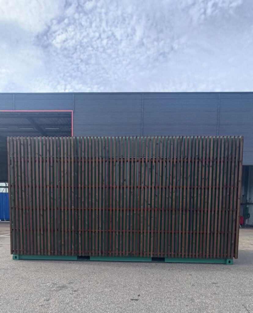 Mobil fjärrvärmestation byggd av container med träklädd baksida i vertikala ribbor.