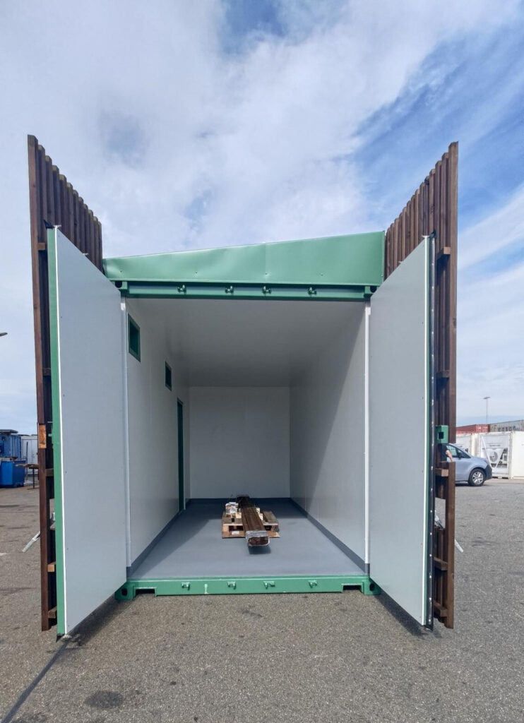 Mobil fjärrvärmestation i container med träfasad, fotograferad från sidan.