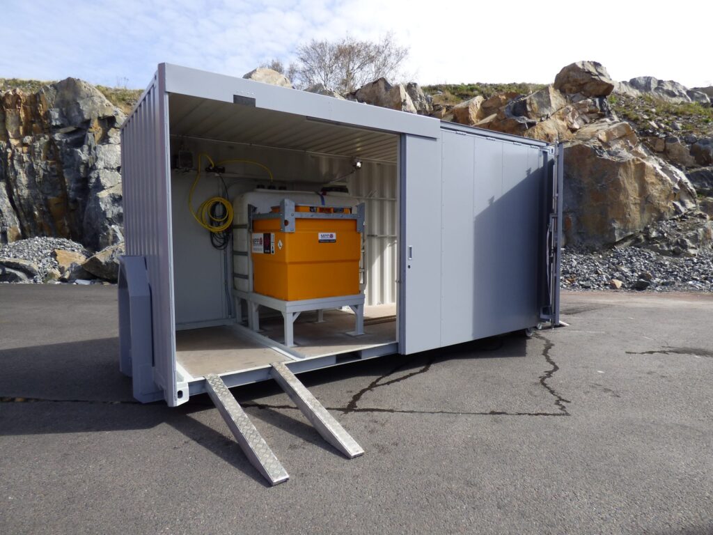 Asfaltscontainer med öppen skjutdörr och utfälld aluminiumramp på arbetsplats