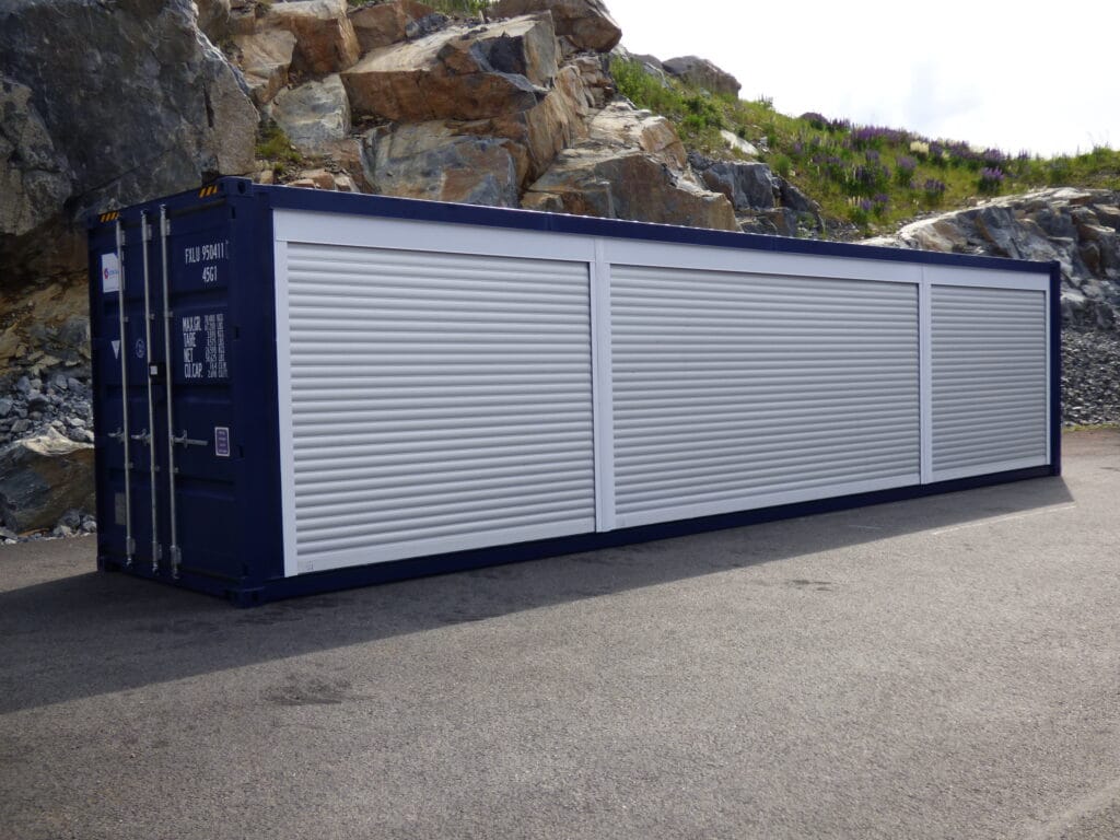 Blå butikscontainer med tre stängda jalusier längs långssidan, byggd av LCS för säsongshandel