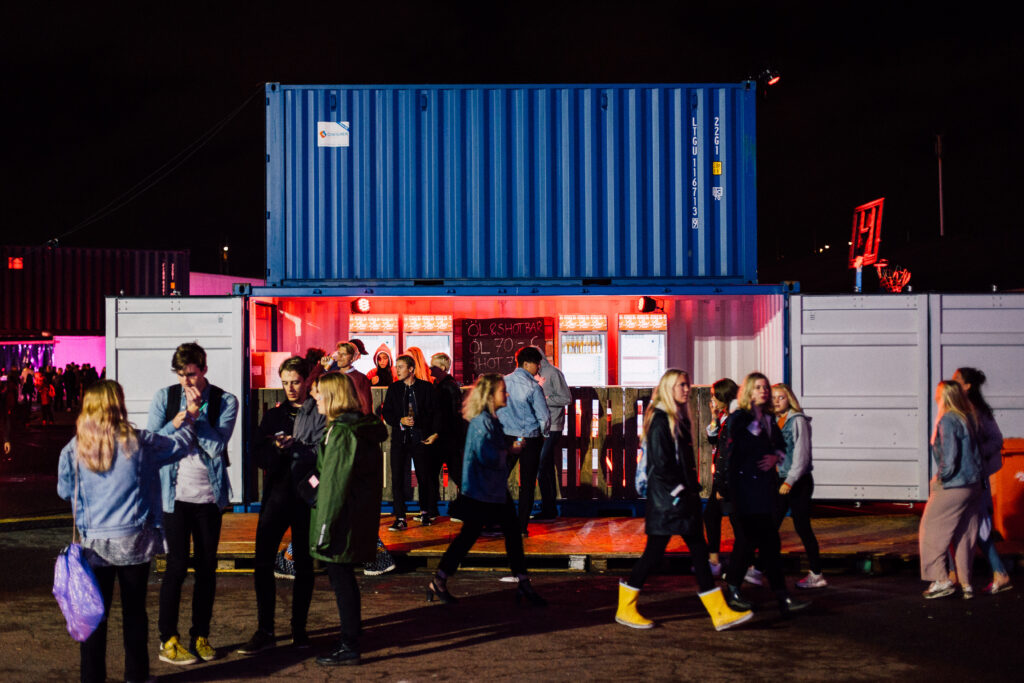 Container som dryckesbar med publik och röd belysning på festival, levererad av LCS