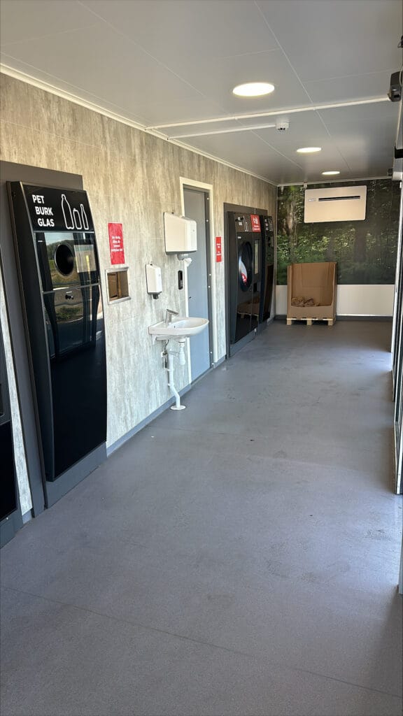Interiör kundyta i pantstationscontainer med pantmaskiner och handfat, byggd av LCS