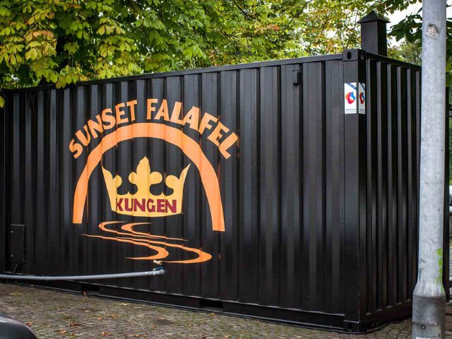 Baksida på svart serveringscontainer med logotyp, placerad på torg, byggd av LCS