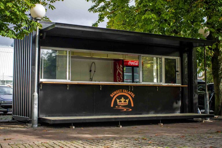 Framsida på serveringscontainer med utfällt golv och glasparti mot kunder på torg, byggd av LCS