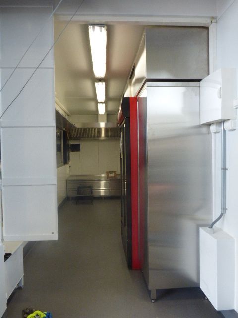 Längsgående vy av köksdelen med kylskåp och rostfria ytor i serveringscontainer byggd av LCS