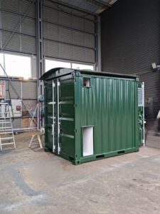 Frontvy på grön ställverkscontainer med ventilationsgaller, fotograferad i LCS verkstad