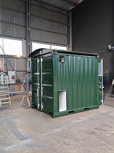 Frontvy på grön ställverkscontainer med ventilationsgaller, fotograferad i LCS verkstad