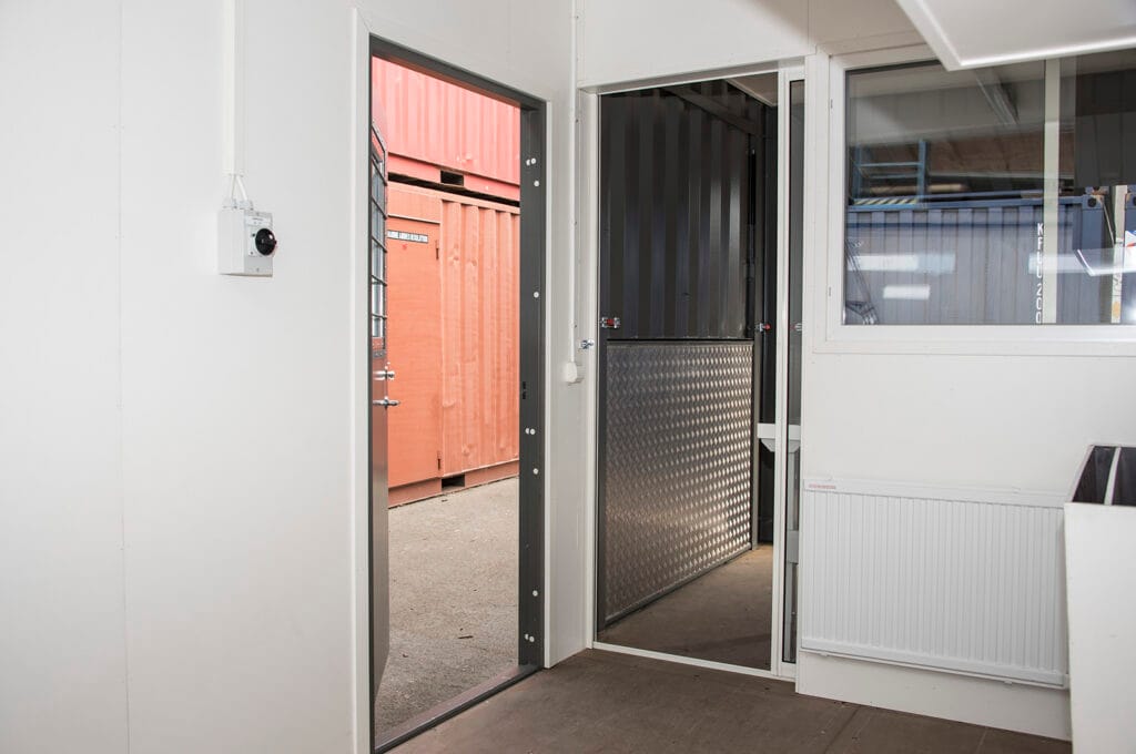 Detalj på gångdörr och skiljevägg med lucka i utbildningscontainer byggd av LCS