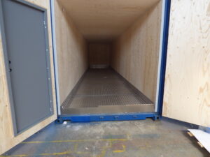 Vattenreningscontainer med aluminiumbalja, plywoodbeklädda väggar med öppna containerdörrar och en installerad gångdörr, byggd av LCS