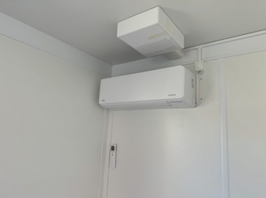 Värmepump En vit värmepump som installerats i en container